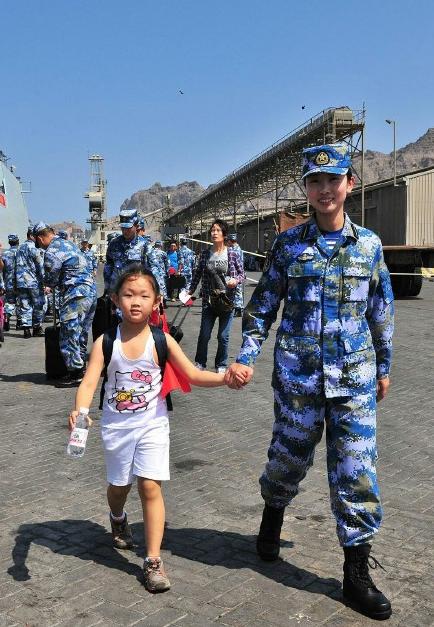 2015年3月，也门，海军女战士牵着一名小女孩的手准备登上军舰。